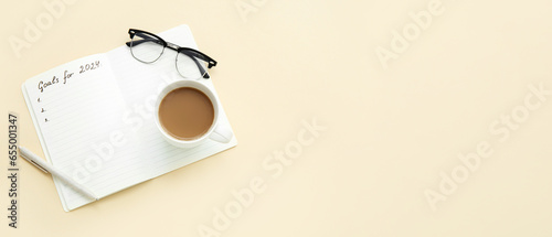 Notebook with empty to do list for year 2024, eyeglasses and cup of coffee on light background. New year goals photo