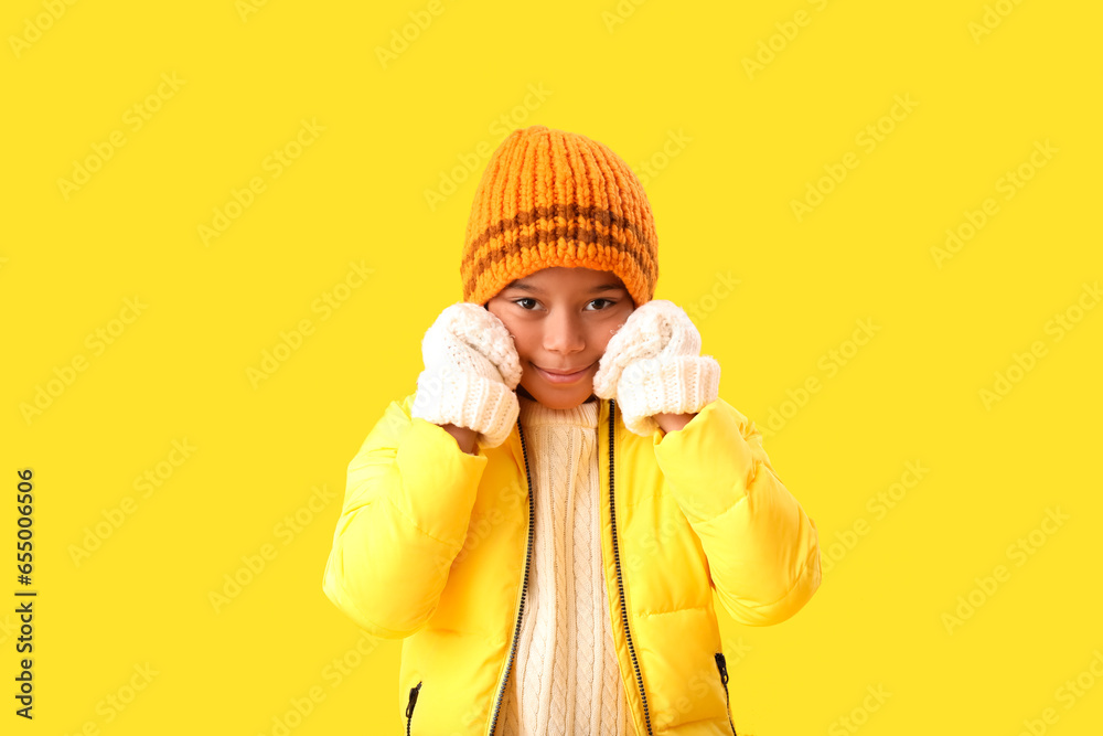 Cute African-American boy in warm winter clothes on yellow background Cute African-American boy in warm winter clothes on yellow background