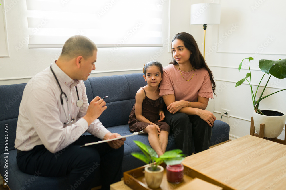 Pediatrician talking to the kid and mother during a doctor's visit Pediatrician talking to the kid and mother during a doctor's visit