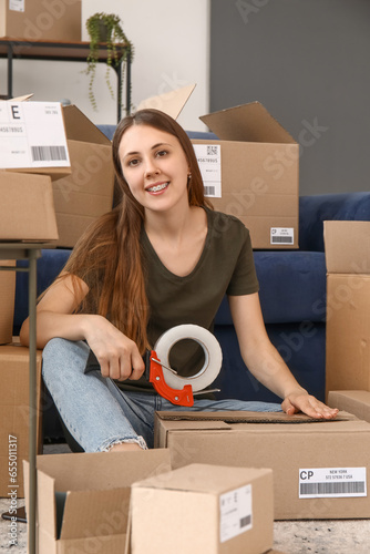 Young woman taping parcel f...