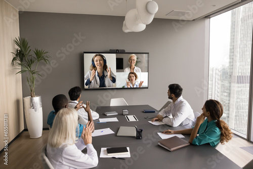 Wide shot of boardroom with clinic staff of doctors talking online and offline, meeting for medical discussion, healthcare Internet council, watching educational webinar photo