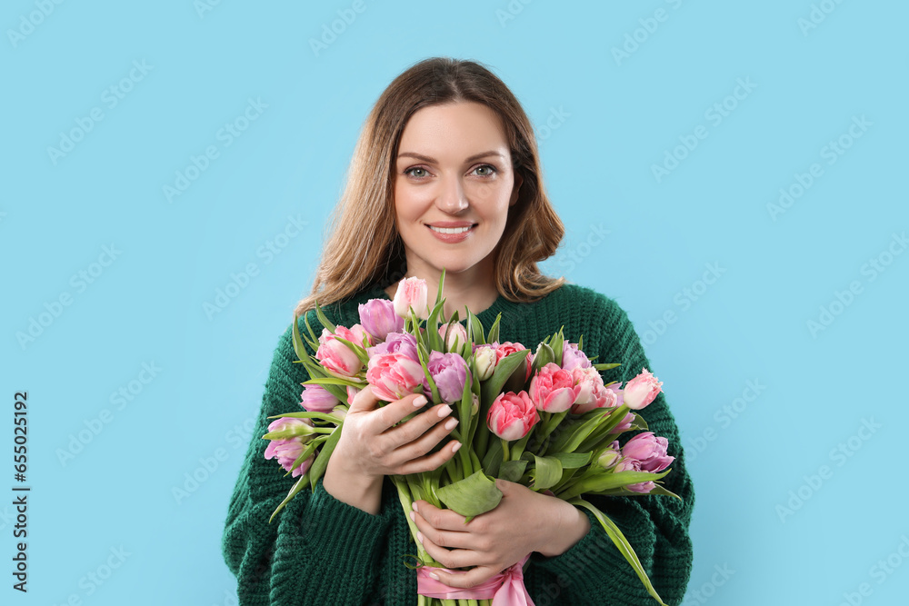 Happy young woman with bouquet of beautiful tulips on light blue background Happy young woman with bouquet of beautiful tulips on light blue background