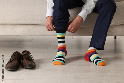 Man putting on colorful socks indoors, closeup