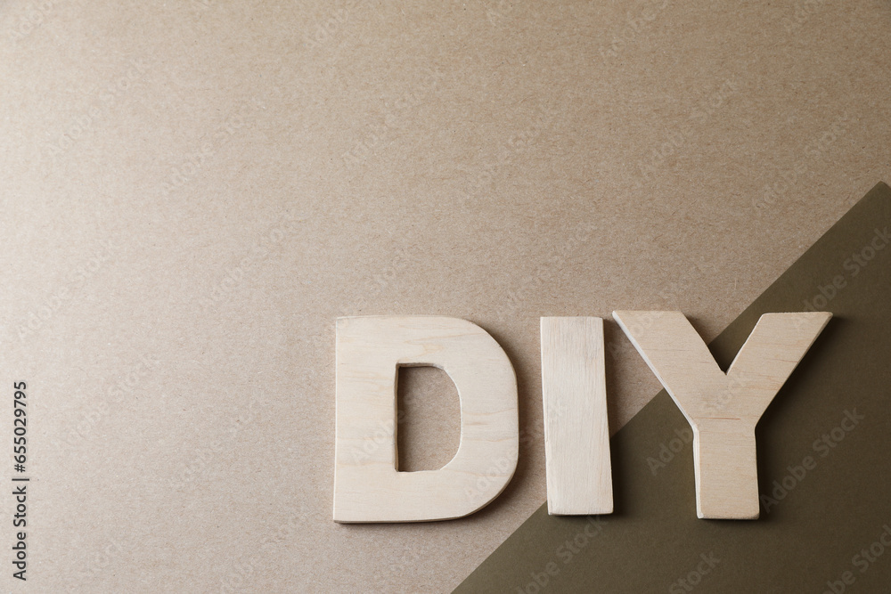 Abbreviation DIY made of wooden letters on color background, flat lay. Space for text
