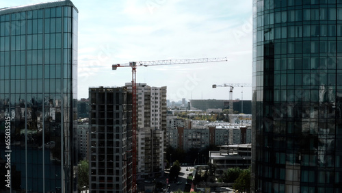 Summer landscape on a built-up city from a height. Stock footage. High-rise beautiful glass offices standing on the banks of the river and green parks for walking and a visible road for traffic.
