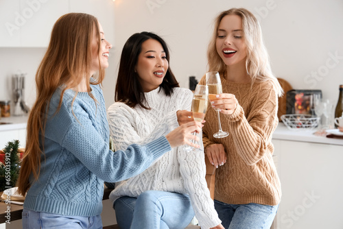 Young women with champagne celebrating Christmas in kitchen