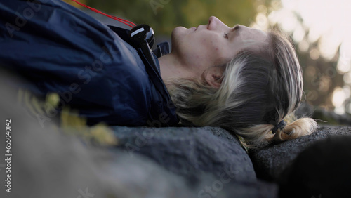 Man lying on stones with closed eyes with blurred forest leaves on the background. Stock. Man relaxing in nature.
