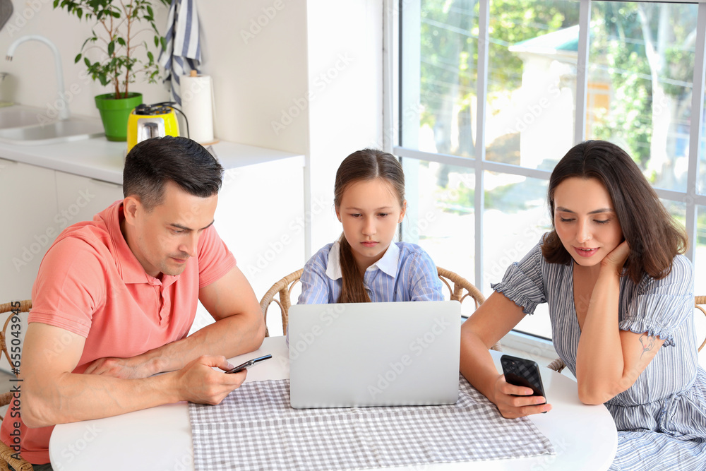 Family involved with gadgets resting at table in kitchen Family involved with gadgets resting at table in kitchen