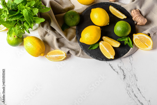Board with different ingredients for preparing fresh lemonade on white marble background