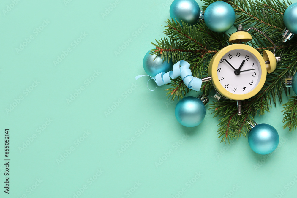 Alarm clock and Christmas tree branches with balls on turquoise background