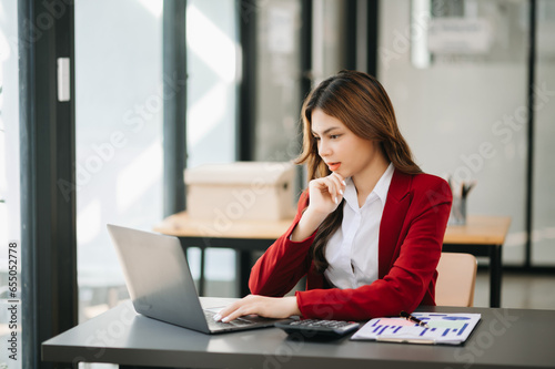 Successful Asian Businesswoman Analyzing Finance on Tablet and Laptop at modern Office Desk tax, report, accounting, statistics, and analytical research concept.
