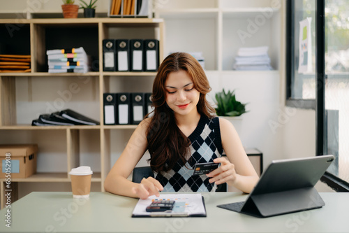 businesswoman hand using smart phone, tablet payments and holding credit card online shopping, omni channel, digital tablet docking keyboard computer at office in sun light.. © Nuttapong punna