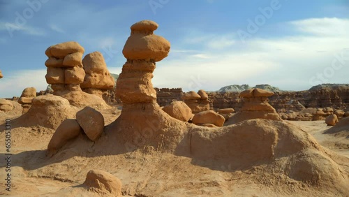 Slow panning view of the hoodoos in Goblin Valley as the sun glows from the formations.