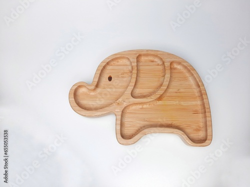 Wooden plate on white background. Baby food equipment in the shape of an elephant character