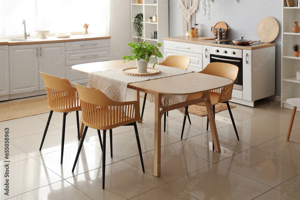 Interior of light kitchen with white counters and dining table