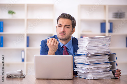 Young male employee and too much work in the office