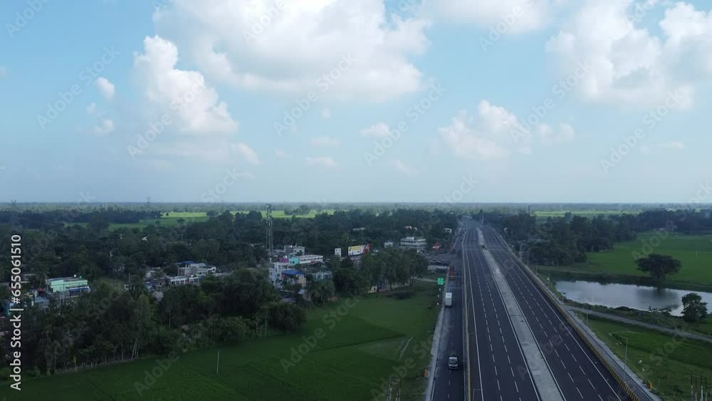 aerial drone shot video of a national highway passing through green farmland across a village in India aerial drone shot video of a national highway passing through green farmland across a village in India