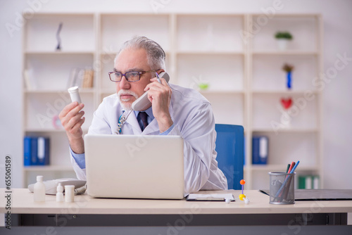 Old male doctor in telemedicine concept