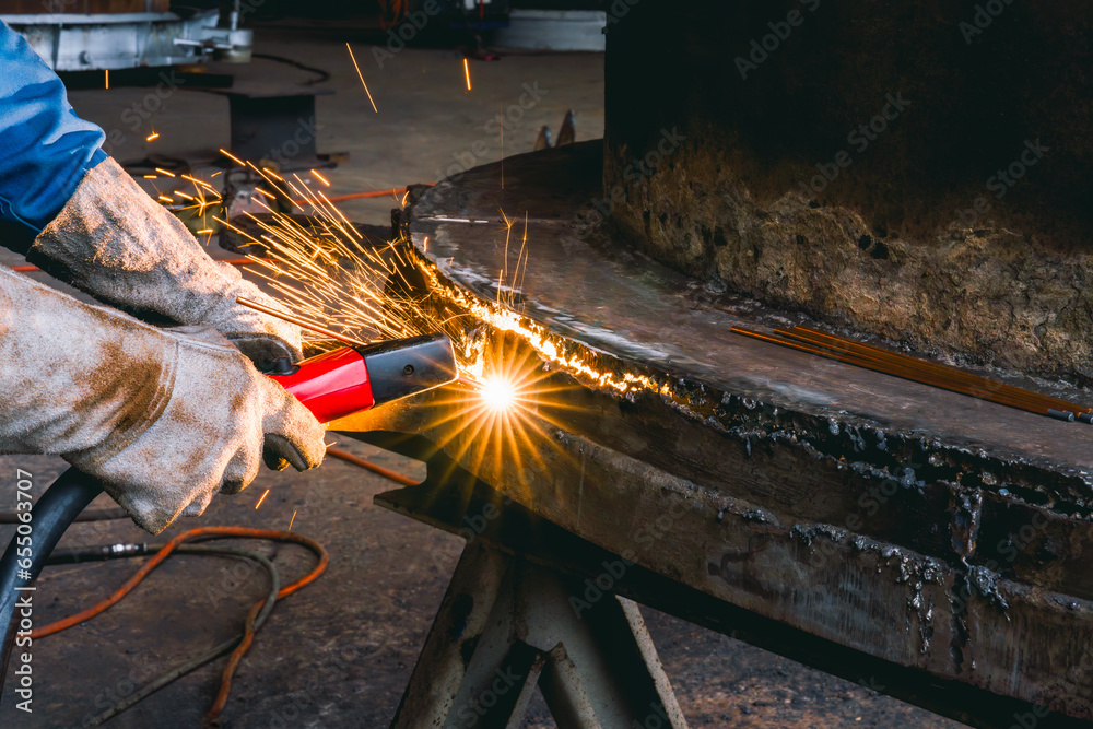 Tableau sur toile Welder use carbon air arc gouging for hot work cutting or gouging heavy metal steel structure in the fabrication factory