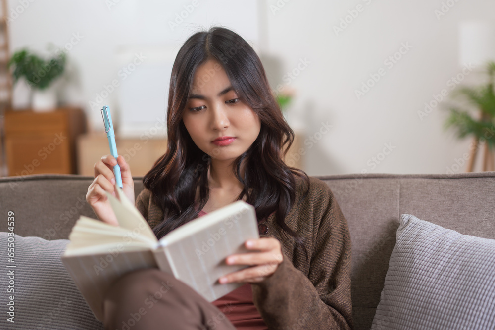 Women leisure on sofa to thinking about something and writing down on notebook in lifestyle at home Women leisure on sofa to thinking about something and writing down on notebook in lifestyle at home