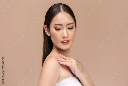 Beautiful Asian woman touching eyebrow smile with clean and fresh skin Happiness with positive emotional,isolated on Beige background,Beauty Cosmetics and spa Facial treatment Concept.