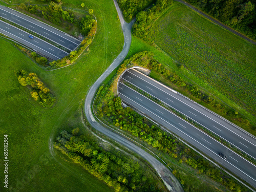 Aerial view of a green bridge ecoduct for fauna crossing above the highway.