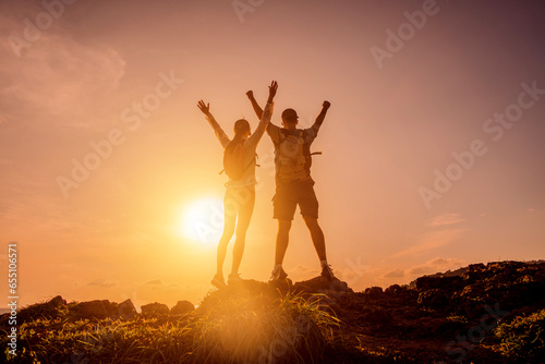 Happy young couple climbs to the top in the mountains near the ocean