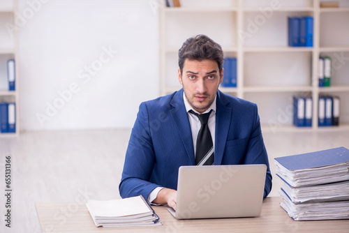 Young male employee and too much work in the office