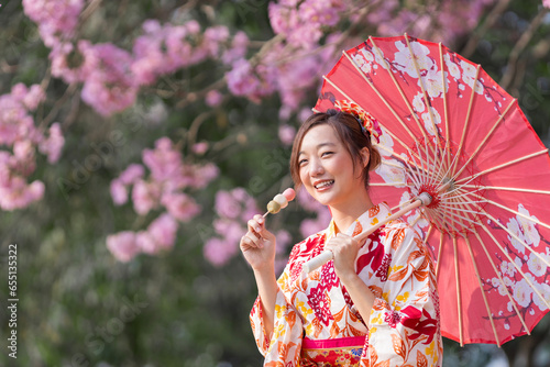 Quadro su tela Japanese woman in traditional kimono dress holding umbrella and sweet hanami dan