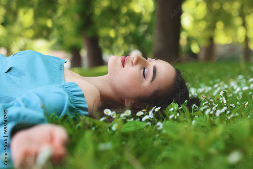 Beautiful woman lying on green grass in park. Spring sunny day Beautiful woman lying on green grass in park. Spring sunny day