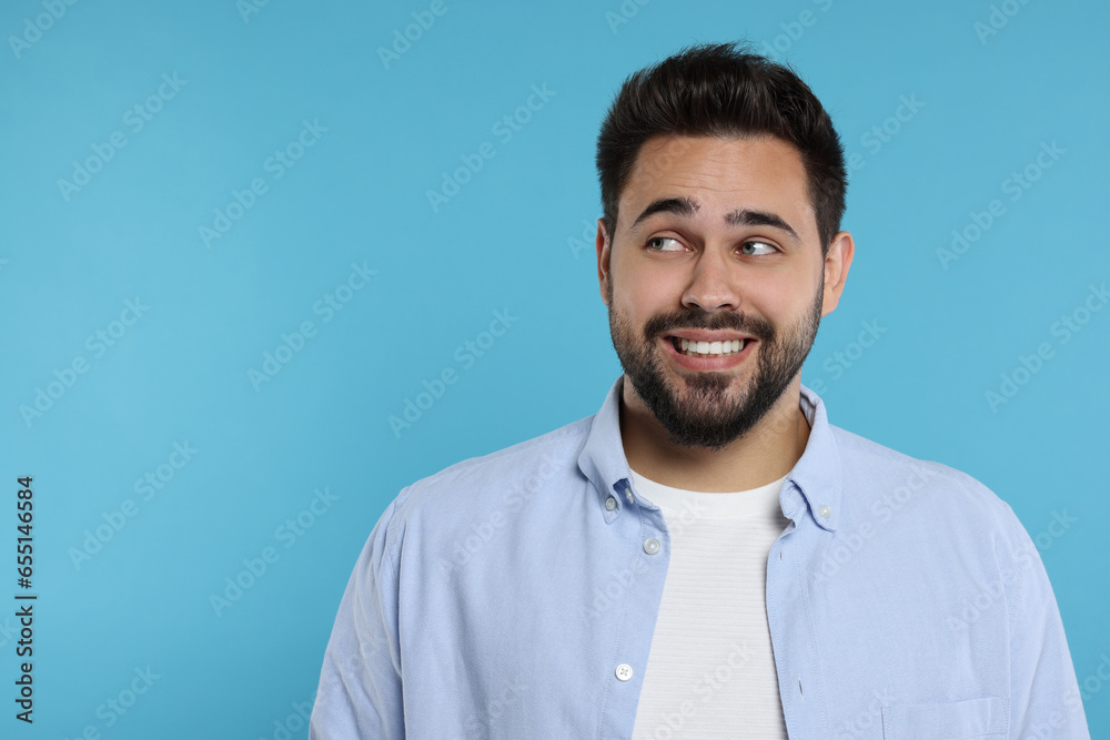 Embarrassed man on light blue background. Space for text Embarrassed man on light blue background. Space for text