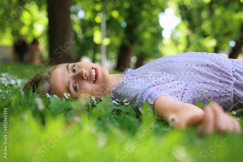 Beautiful woman lying on green grass in park. Spring sunny day