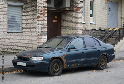 An old broken dark blue car stands near the brick wall of a residential building  Iskrovsky Prospekt  Saint Petersburg  Russia  September 29  2023