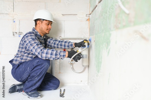 Indian plumber installing water equipment - meter, filter and pressure reducer