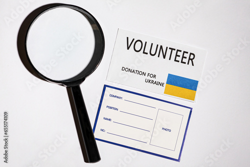 Picture on a white background with a magnifying glass and two accreditation cards for the support of Ukraine.