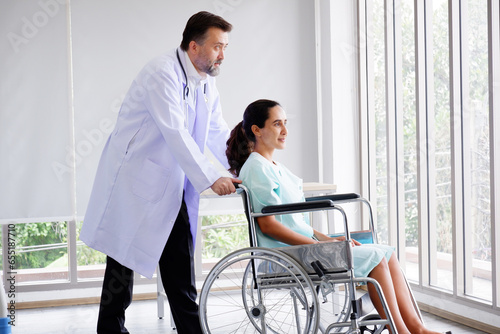 Doctor caring for a female patient sitting in a wheelchair.