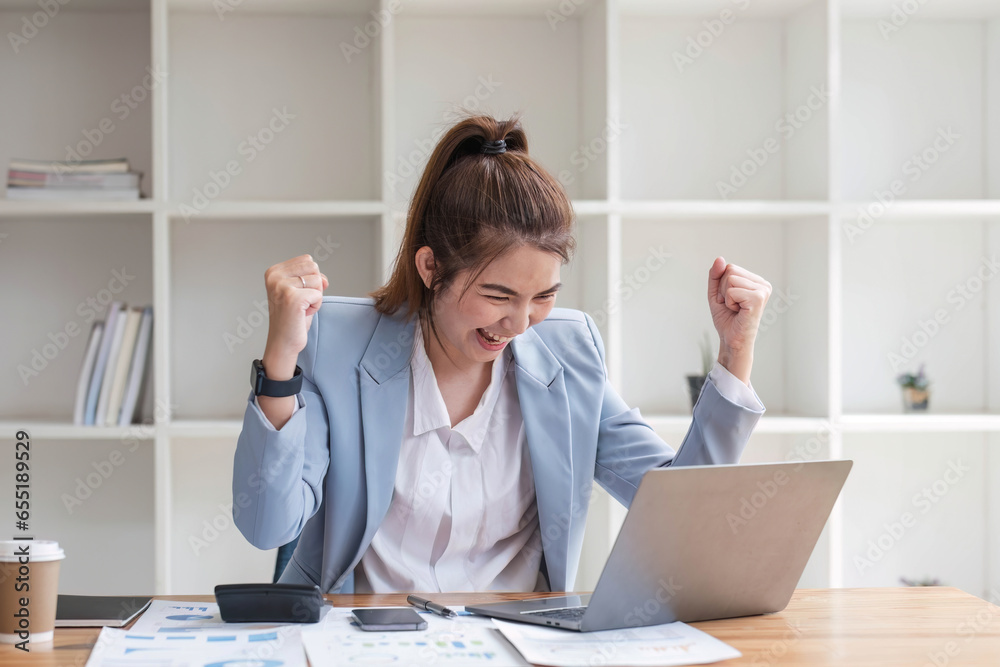 Asian businesswomen show joyful expression of success at work smiling happily with a laptop computer in a modern office. Asian businesswomen show joyful expression of success at work smiling happily with a laptop computer in a modern office.