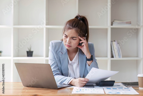 Confused Asian woman thinking hard about how to solve problems online looking at laptop screen. Serious Asian businesswoman worried focused on solving difficult computer at office