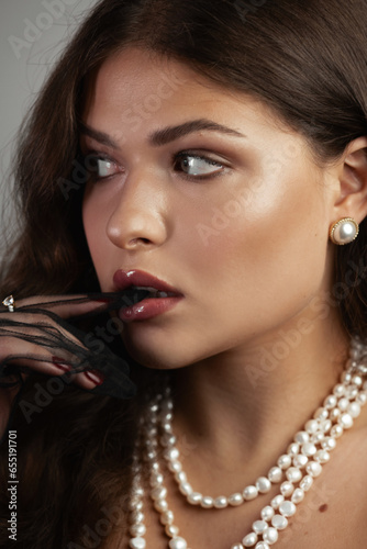 Portrait of young beautiful woman with long shine hair and bright makeup. Studio shoot. Gray background. vertical.