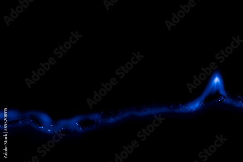 blue burning paper, glowing edge of paper on a black background