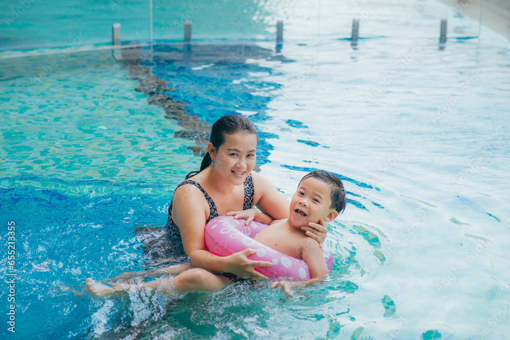 Happy Asian mother and son posing at swimming pool