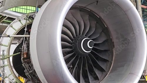 Aviation industry aircraft open engine cover for maintenance and blades of jet turbine rotating by wind.