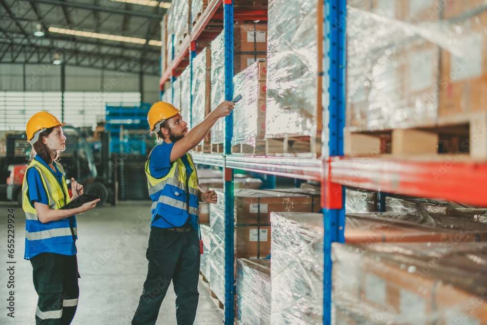 Fototapeta premium Warehouse staff verify automotive, paper items using handheld device, ensuring precise shipment.