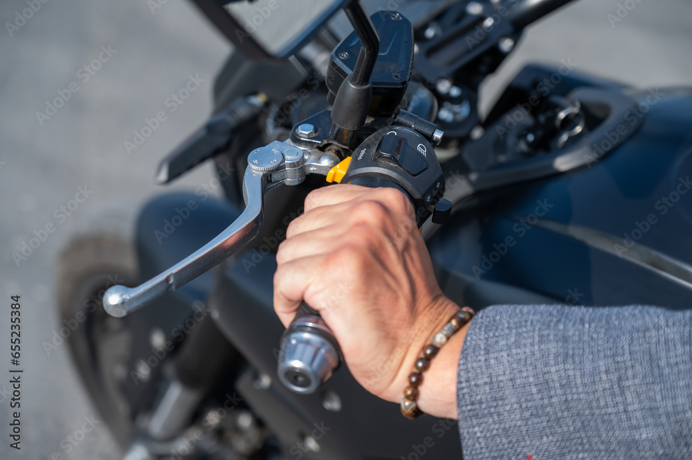 Caucasian man rides an electric motorcycle. Close-up of a man's hand pressing the gas on the steering wheel. Caucasian man rides an electric motorcycle. Close-up of a man's hand pressing the gas on the steering wheel.