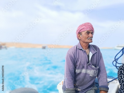 The photo features an old sailor with a white mustache who is a retired soldier in the navy wearing a Bedouin scarf on his head