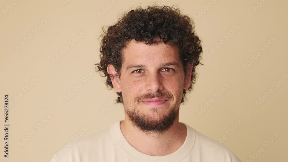 Close-up, man raising his head and looking at the camera with smile on beige background Close-up, man raising his head and looking at the camera with smile on beige background