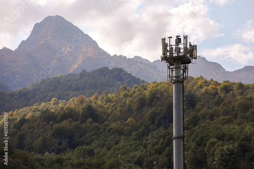 Metal structure, communication tower in a mountainous area, against the background of high mountain peaks. Russia, Krasnaya Polyana, Sochi.