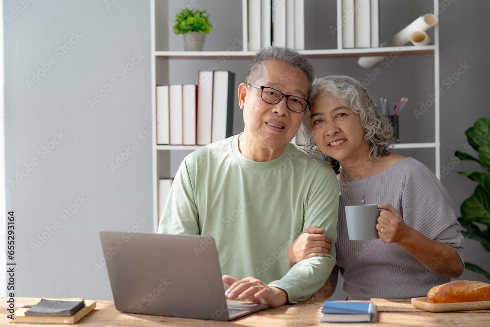 Happy mature couple using laptop at home. Happy elderly Asian couple laughing bonding together sitting at home table with laptop. Happy mature couple using laptop at home. Happy elderly Asian couple laughing bonding together sitting at home table with laptop.