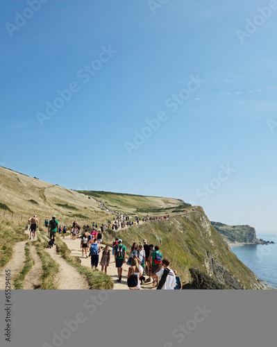 High Angle View of Lots of People are Walking on Mountain at Durdle Door Landscape and Sea View of British Tourist Attraction, England UK. Captured on September, 9th, 2023