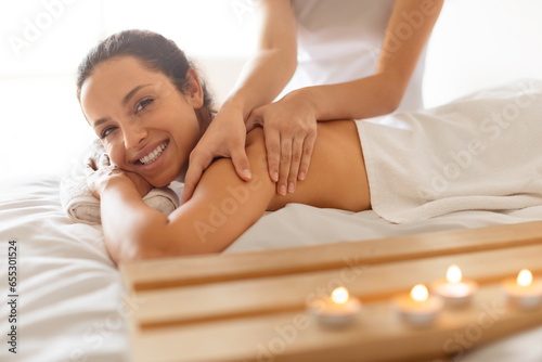 Lady having body massage lying on table at spa salon